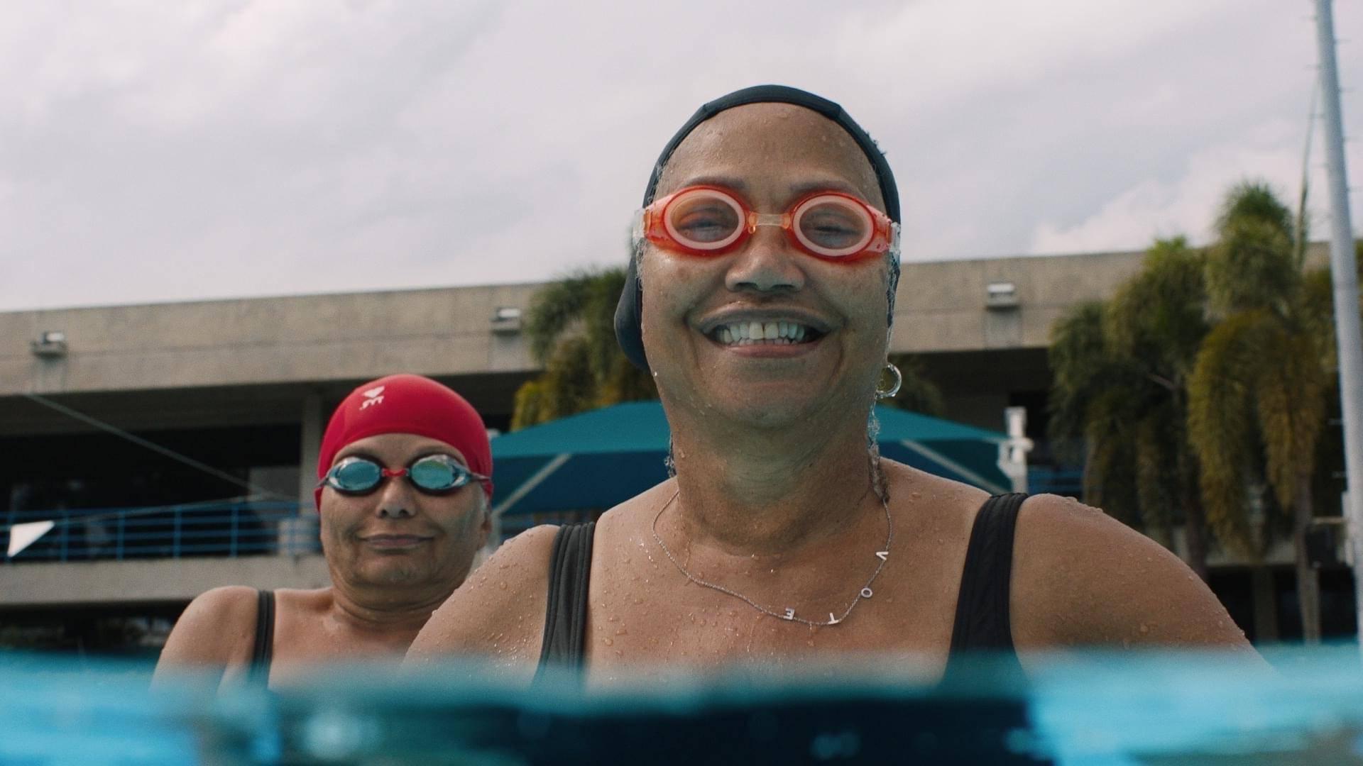 two older women in pool with goggles and swim caps on